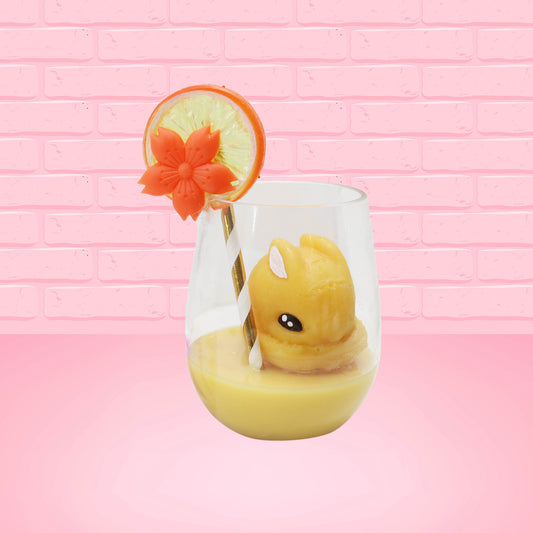 Cute kawaii bunny Screwdriver orange drink inside a glass with a gold white straw with an orange slice and orange flower on the rim of the glass. The view is from the front at an angle.