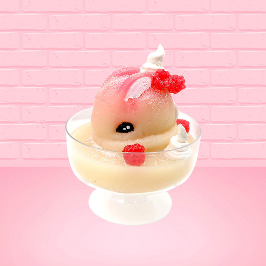 Cute kawaii bunny raspberry cheesecake white ice cream with raspberries and whipped cream swirls in the dish. The bunny has two raspberry on the back near the swirl of whipped cream and covered with white glitter. This view is from the side.