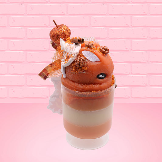 Cute kawaii bunny orange ice cream tall sundae that has orange tulle, a fall colored bow with a pumpkin in the middle, brown pecan halves, cinnamon twig on the whipped cream on top, and a glittery pumpkin stuck into the dish. This view is from the side.