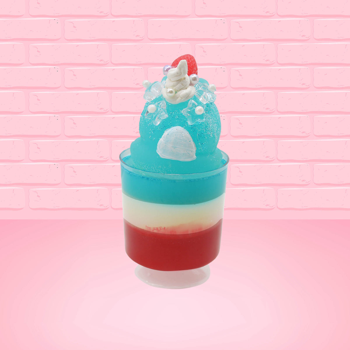 Cute kawaii bunny blue ice cream tall sundae that has red, white and blue layers in the dish and a strawberry on top near the whipped cream and pearls. The photo is taken from the back.