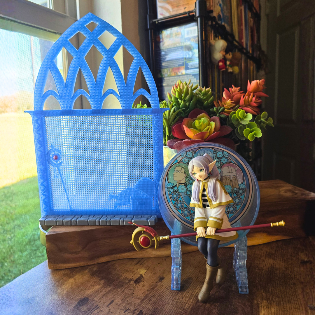 Silk Ice Blue Frieren Room enamel pin board next to a sitting anime girl figure on top of a desk in a room. 