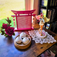 Japanese Arch Enamel pin board on top of a desk next to girl anime figure, flowers, hot dumpling toy by a window.