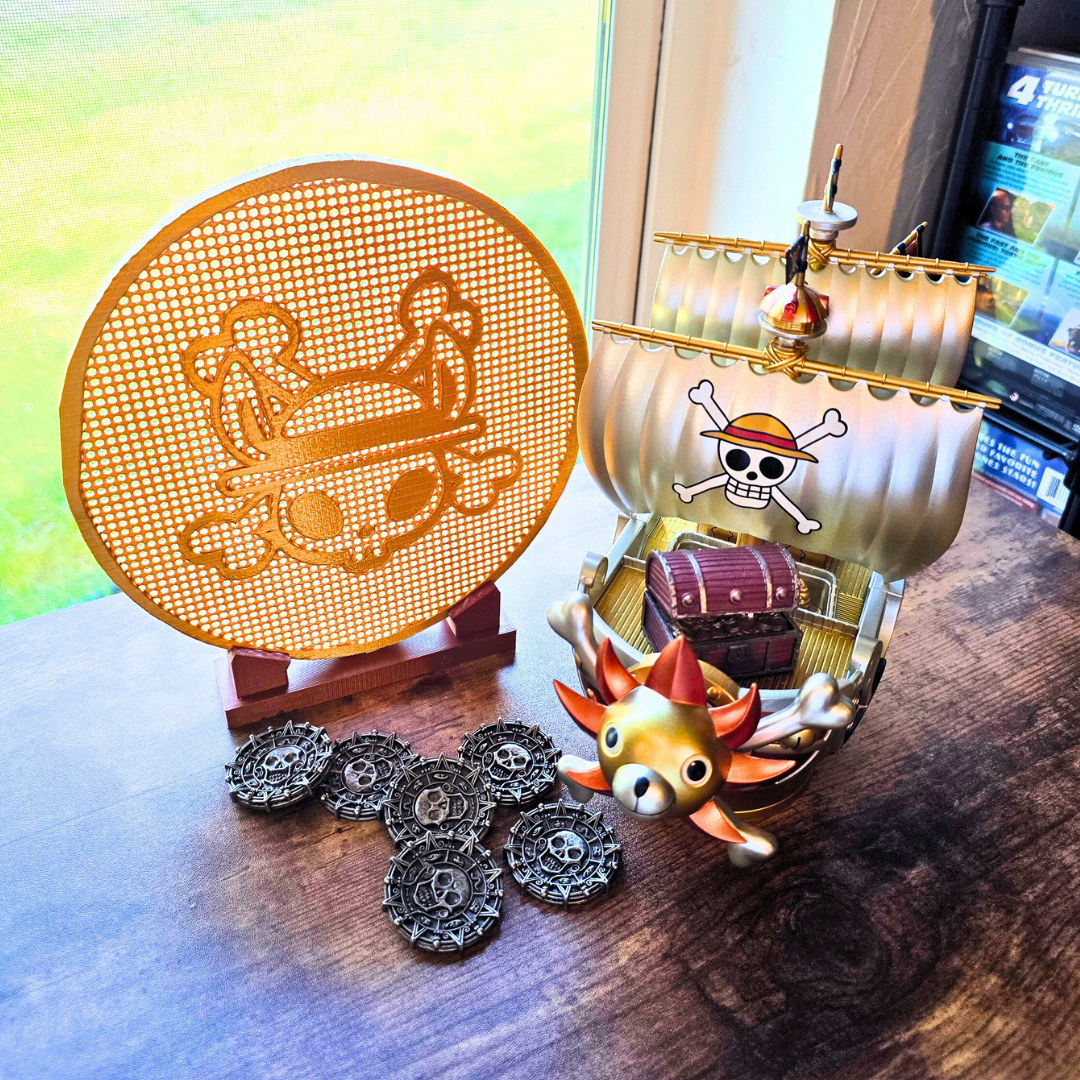 Gold pirate bunny coin enamel pin display board next to some pirate coins and a pirate ship on top of a desk.