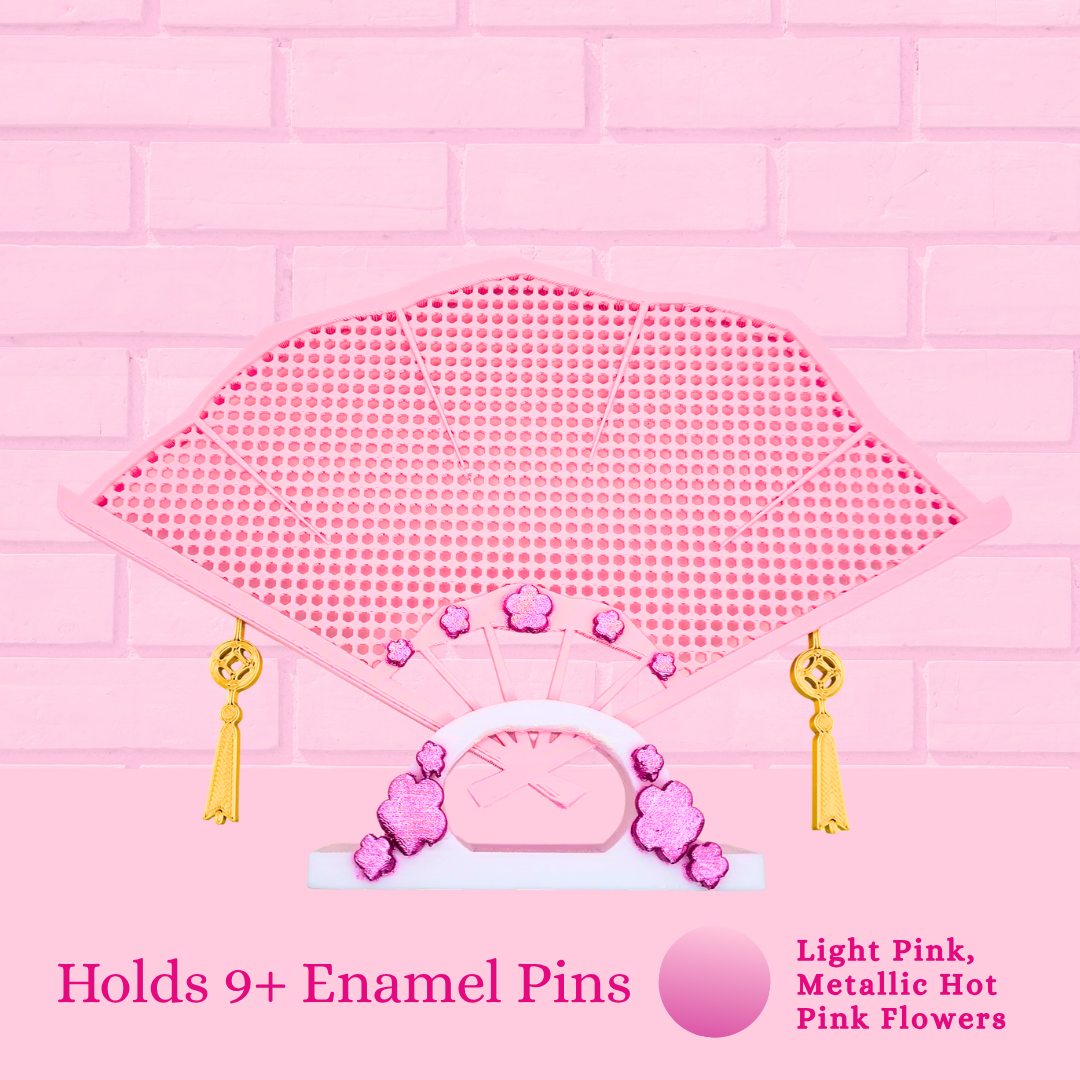 Light pink Japanese fan close up with the words holds 9+ enamel pins.