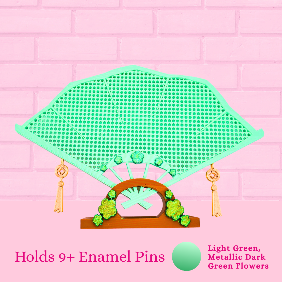 Light green Japanese fan close up with the words holds 9+ enamel pins.