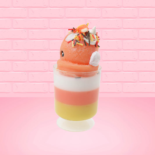 Cute kawaii bunny tall orange, white, and yellow ice cream sundae with yellow, brown, and orange sprinkles on top.  The top also has two pieces of candy corn near the whipped cream swirl. This view is from the back at an angle.