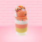 Cute kawaii bunny tall orange, white, and yellow ice cream sundae with yellow, brown, and orange sprinkles on top.  The top also has two pieces of candy corn near the whipped cream swirl. This view is from the other side.