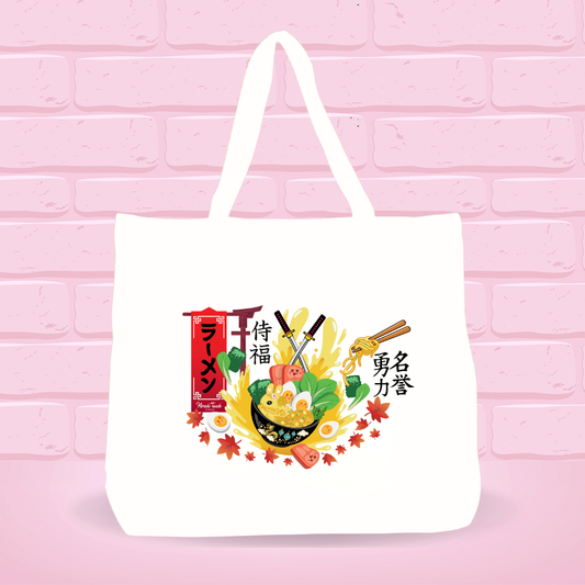 White tote bag with A Samurai Blessing Ramen Bunny bowl design and japanese text on a pink brick wall background.