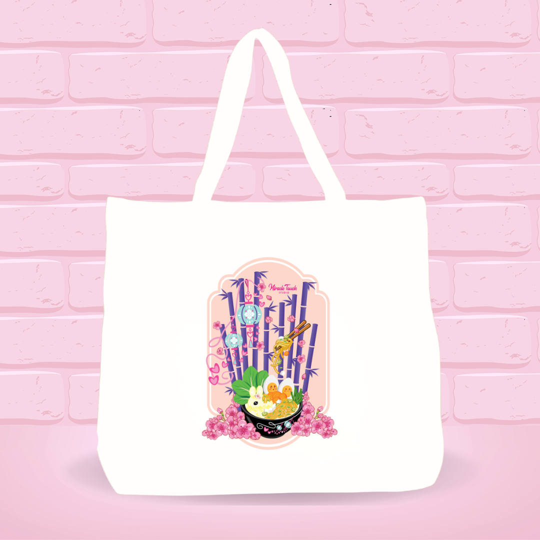 White tote bag with Kong Fu Tofu Heaven Ramen Bunny bowl design on a pink brick wall background.