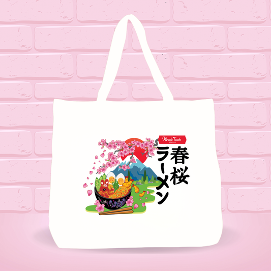 White tote bag with Spring Cherry Blossom Ramen Bunny bowl design and japanese text on a pink brick wall background.