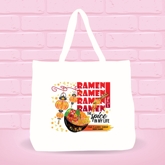White tote bag with Star Flaming Shrimp Ramen Bunny bowl design,  text and quote on a pink brick wall background.