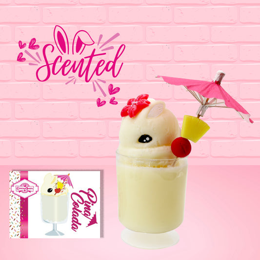 Cute kawaii bunny Pina Colada white drink with a red glittery flower on the top of the bunny in the tall glass. A pink umbrella with a piece of pineapple and cherry sits inside the rim on the side. The front of the character card is shown as well as the word scented.