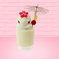 Cute kawaii bunny Pina Colada white drink with a red glittery flower on the top of the bunny in the tall glass. A pink umbrella with a piece of pineapple and cherry sits inside the rim on the side. This view is from the front.