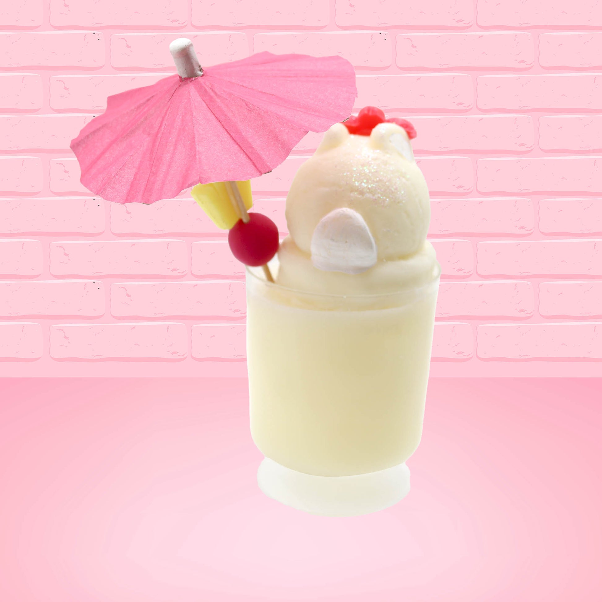 Cute kawaii bunny Pina Colada white drink with a red glittery flower on the top of the bunny in the tall glass. A pink umbrella with a piece of pineapple and cherry sits inside the rim on the side. This view is from the back.