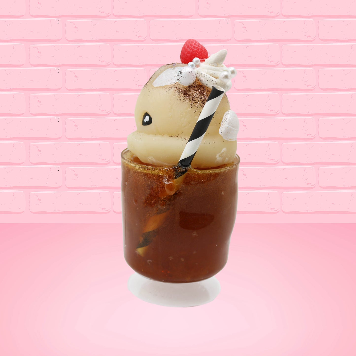 Cute kawaii bunny Root Beer Float white bunny in a brown drink with a black and white straw on the side. The bunny has a strawberry, brown glitter, silver pearls, on top next to the swirl of whipped cream. This view is from the side at an angle.