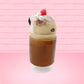 Cute kawaii bunny Root Beer Float white bunny in a brown drink with a black and white straw on the side. The bunny has a strawberry, brown glitter, silver pearls, on top next to the swirl of whipped cream. This view is from the other side.