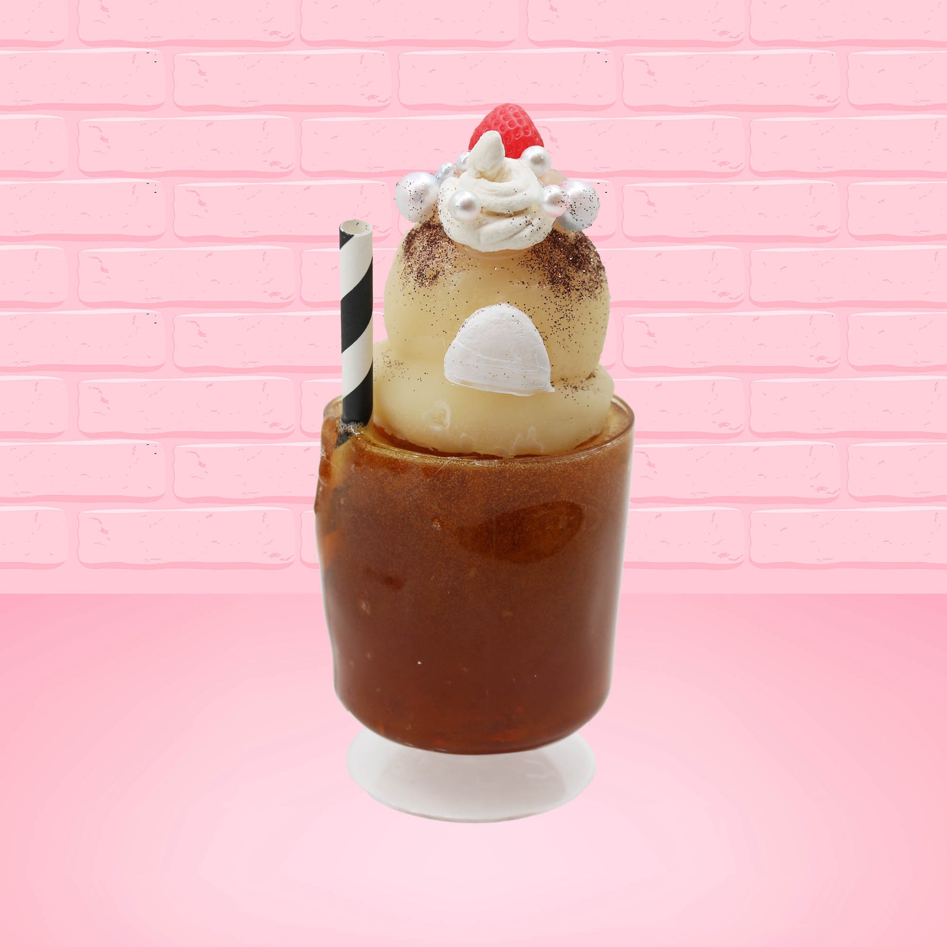 Cute kawaii bunny Root Beer Float white bunny in a brown drink with a black and white straw on the side. The bunny has a strawberry, brown glitter, silver pearls, on top next to the swirl of whipped cream. This view is from the back.