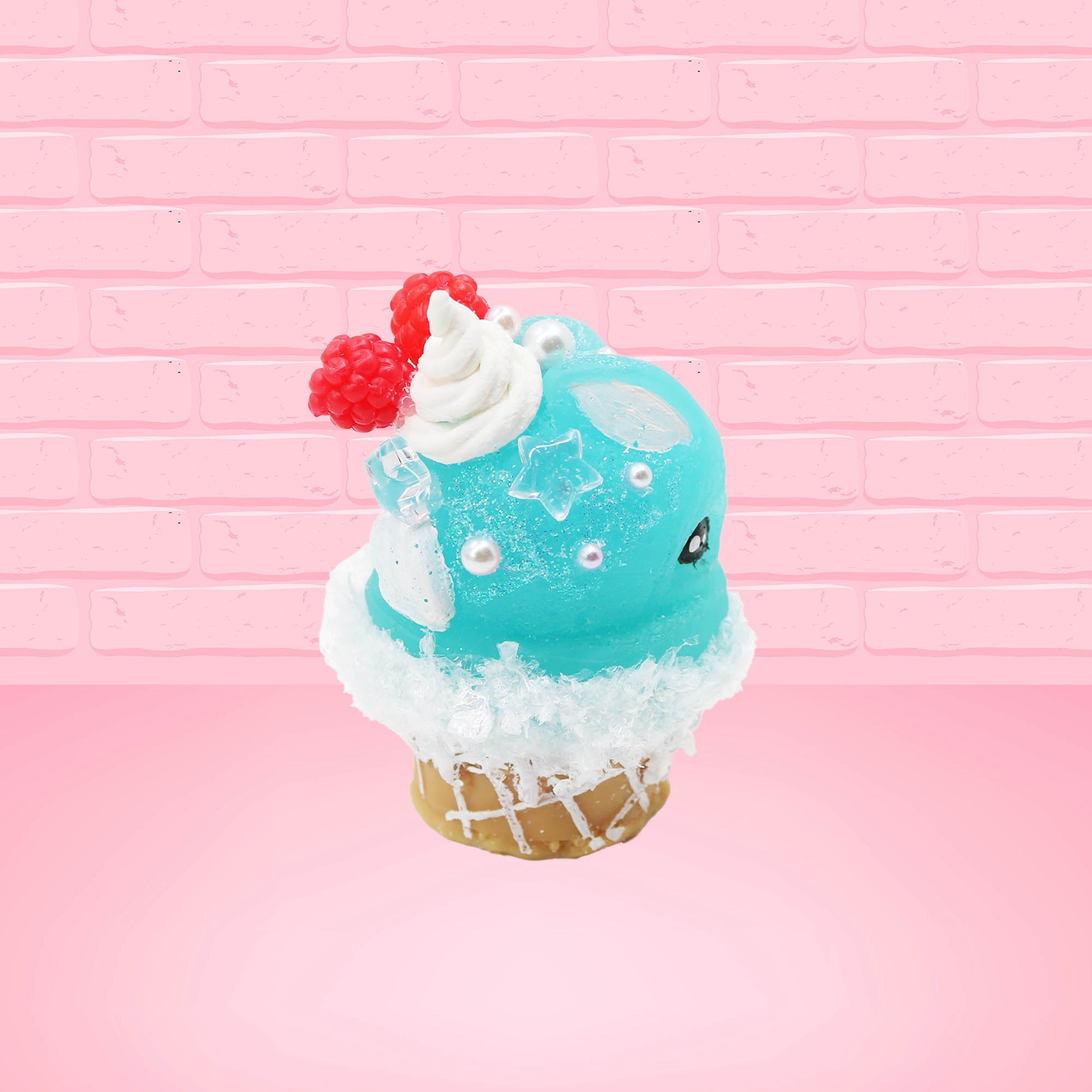 Cute bunny kawaii Blue Razz Star Blast blue ice cream with red raspberries, silver pearls and clear stars on the top of the bunny near the whipped cream swirl. This view is from the back at a different angle.