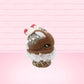 Cute kawaii bunny chocolate ice cream cone with glitter and red raspberries on top of the bunny near the swirl of whipped cream. This view is from the other side.