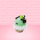 Cute kawaii bunny mint chocolate green ice cream cone with chocolate drizzle and sprinkles near the swirl of the whipped cream, with green mint leaves.  The view is from the other side.