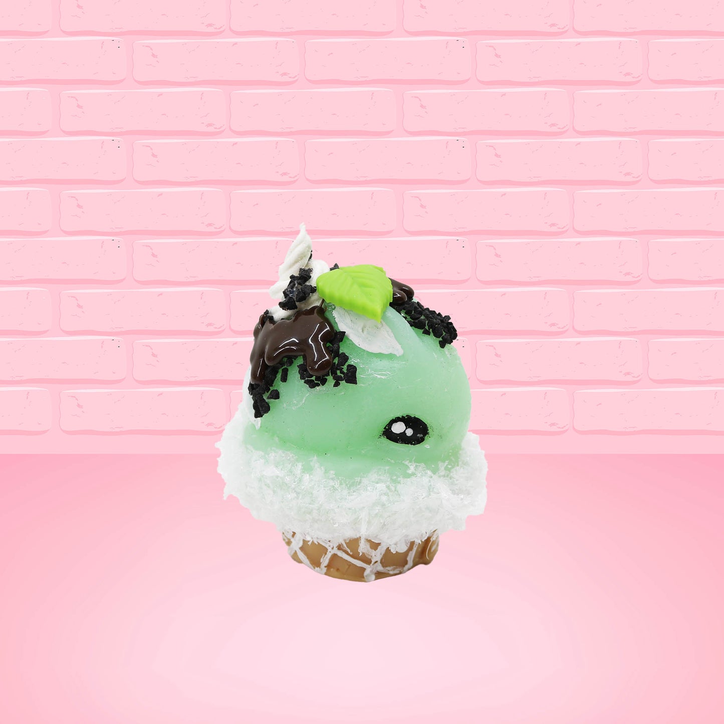Cute kawaii bunny mint chocolate green ice cream cone with chocolate drizzle and sprinkles near the swirl of the whipped cream, with green mint leaves.  The view is from the other side.