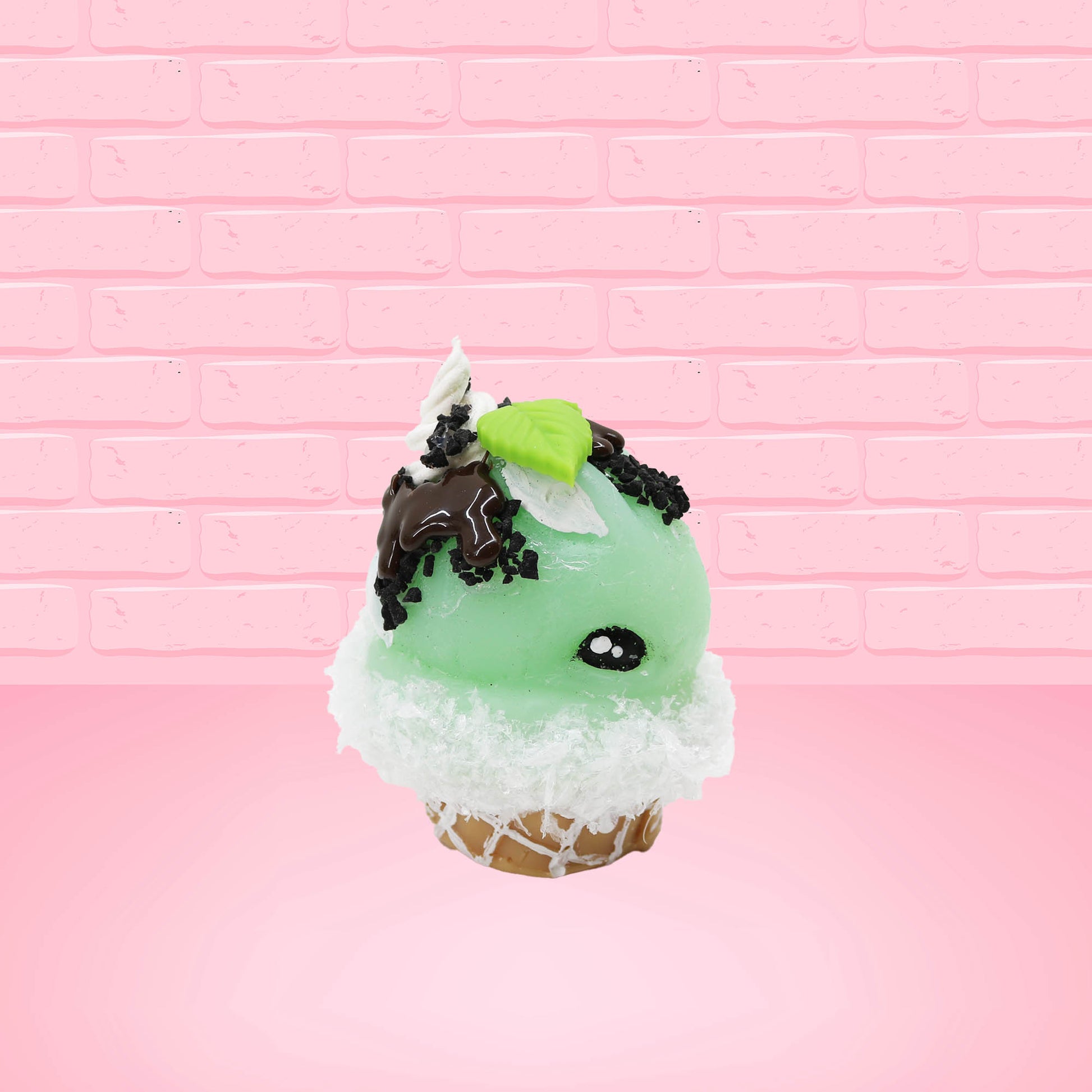 Cute kawaii bunny mint chocolate green ice cream cone with chocolate drizzle and sprinkles near the swirl of the whipped cream, with green mint leaves.  The view is from the other side.