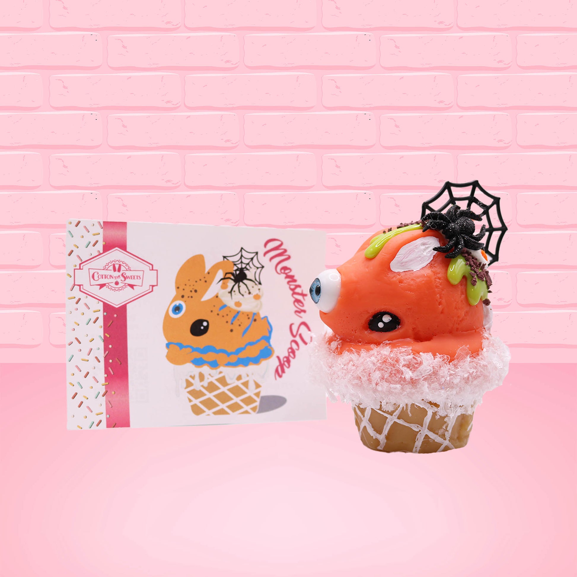 Cute kawaii bunny Monster Scoop orange ice cream cone with a blue eye in the center, green drizzle with chocolate bits, pumpkin sprinkles, a black spider and web near the top of the bunny next to swirl of the whipped cream. The front of the character card is shown.