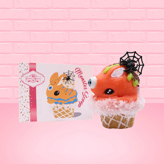 Cute kawaii bunny Monster Scoop orange ice cream cone with a blue eye in the center, green drizzle with chocolate bits, pumpkin sprinkles, a black spider and web near the top of the bunny next to swirl of the whipped cream. The front of the character card is shown.
