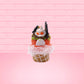 Cute kawaii bunny Monster Scoop orange ice cream cone with a blue eye in the center, green drizzle with chocolate bits, pumpkin sprinkles, a black spider and web near the top of the bunny next to swirl of the whipped cream. This view is from the back.