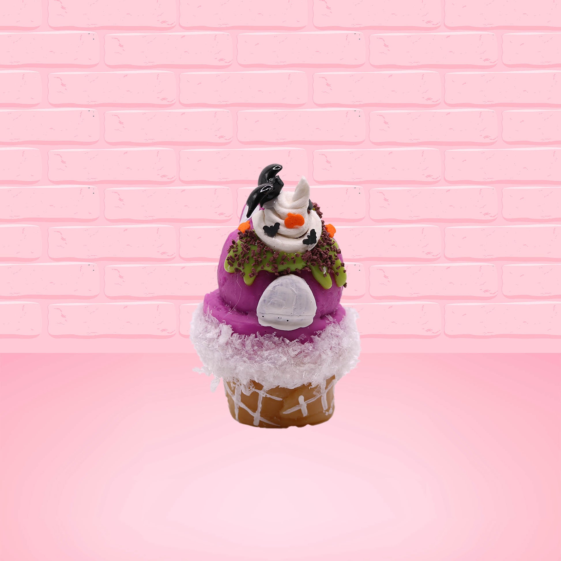 Cute kawaii bunny Monster Scoop purple ice cream cone with a green eye in the center, green drizzle with chocolate bits, pumpkin and bat sprinkles, and a bat on the top of the bunny near the whipped cream swirl. This view is from the back.