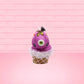 Cute kawaii bunny Monster Scoop purple ice cream cone with a green eye in the center, green drizzle with chocolate bits, pumpkin and bat sprinkles, and a bat on the top of the bunny near the whipped cream swirl. This view is from the front.