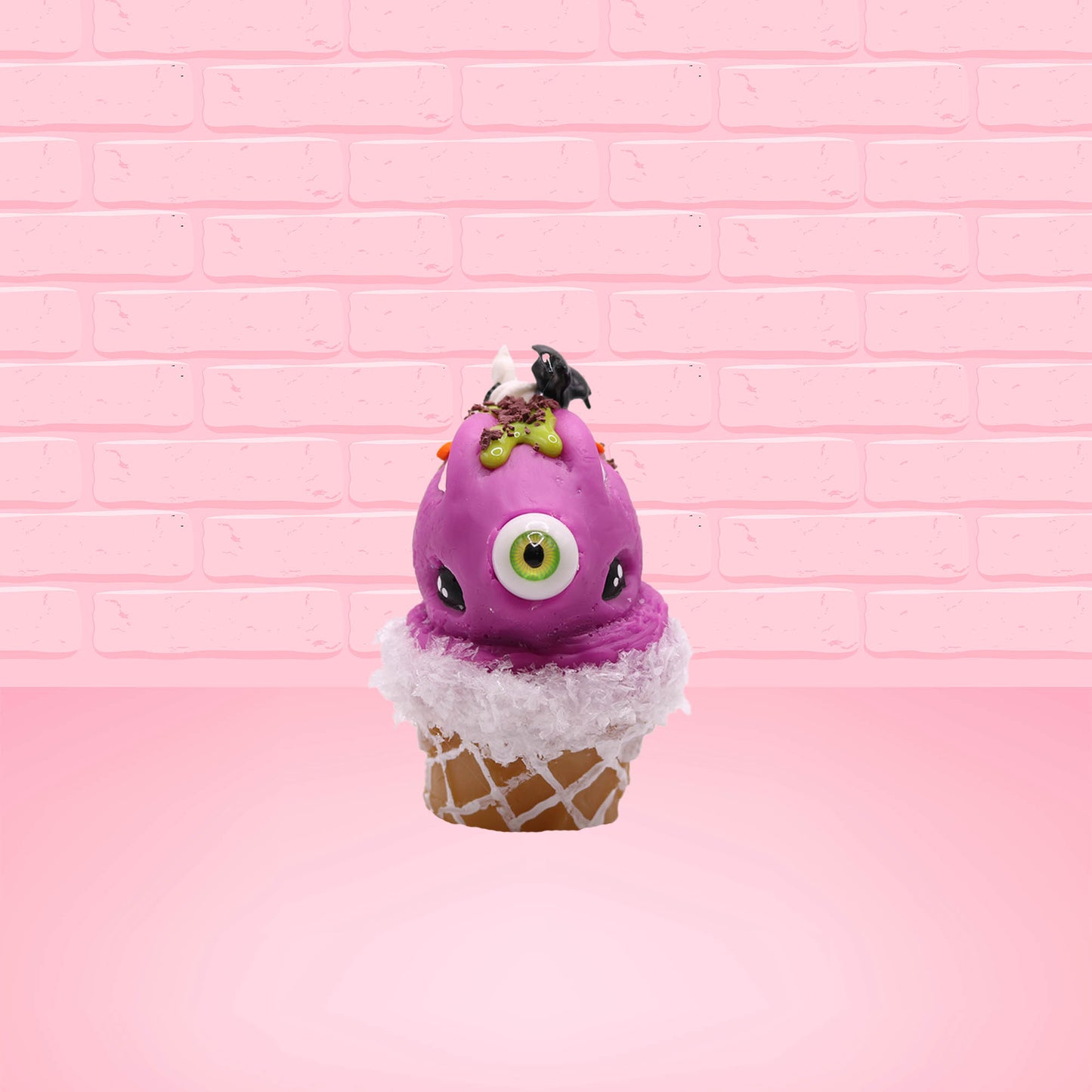 Cute kawaii bunny Monster Scoop purple ice cream cone with a green eye in the center, green drizzle with chocolate bits, pumpkin and bat sprinkles, and a bat on the top of the bunny near the whipped cream swirl. This view is from the front.