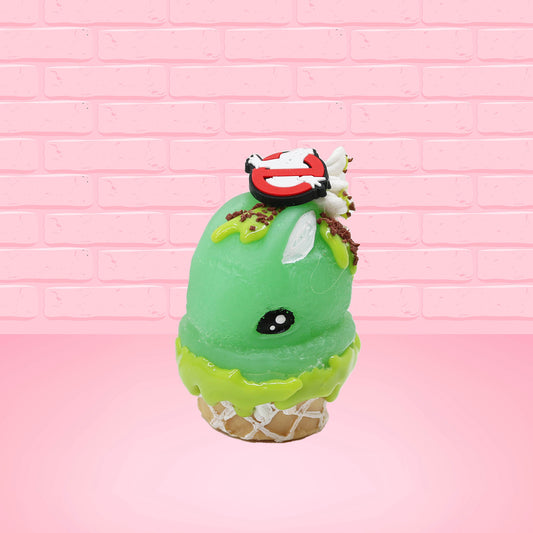 Cute kawaii bunny Slimer Scoop green ice cream cone with green drizzle and brown bits, a ghost buster logo near the whipped cream swirl on top. This view is from the front at an angle.