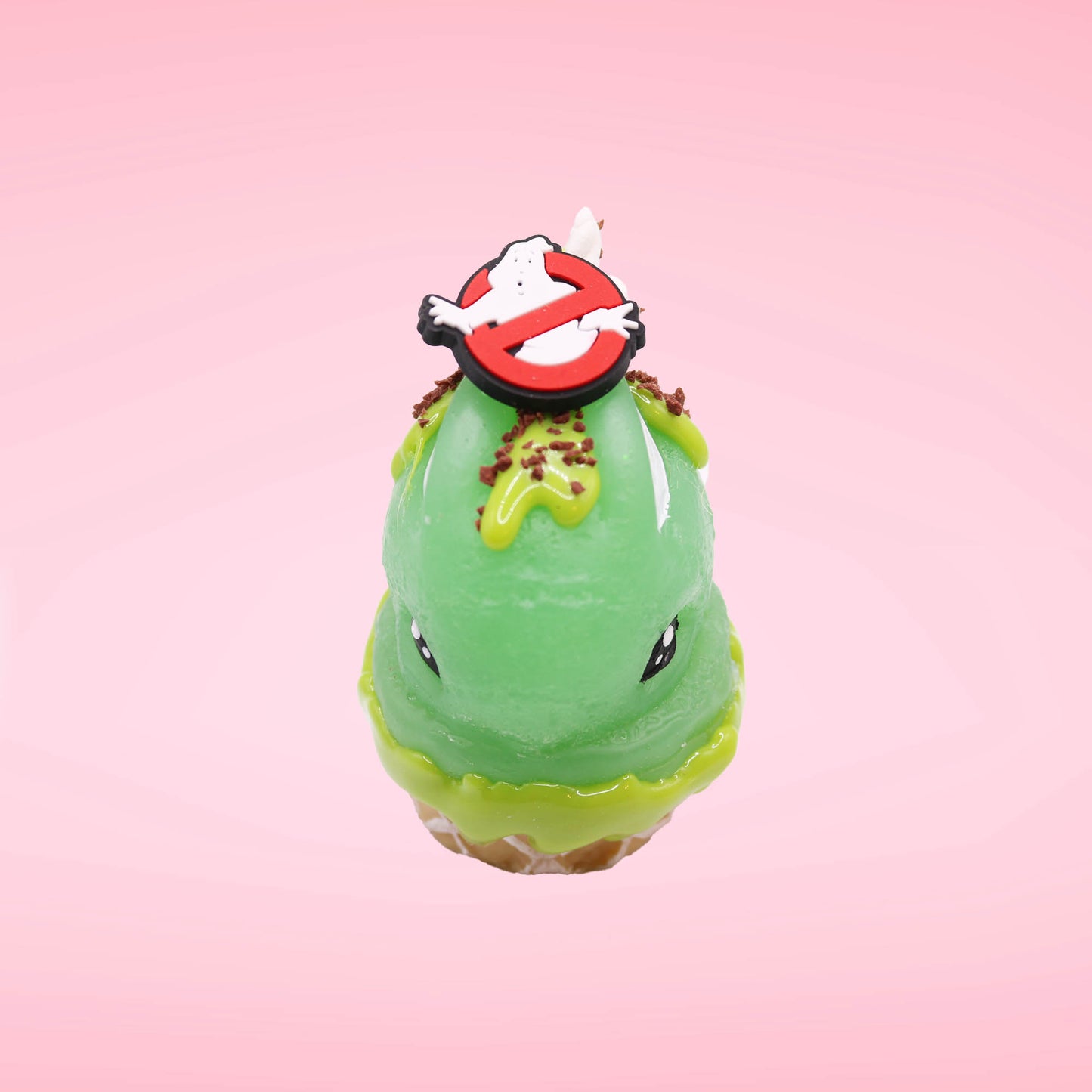 Cute kawaii bunny Slimer Scoop green ice cream cone with green drizzle and brown bits, a ghost buster logo near the whipped cream swirl on top. This view is from the top side.