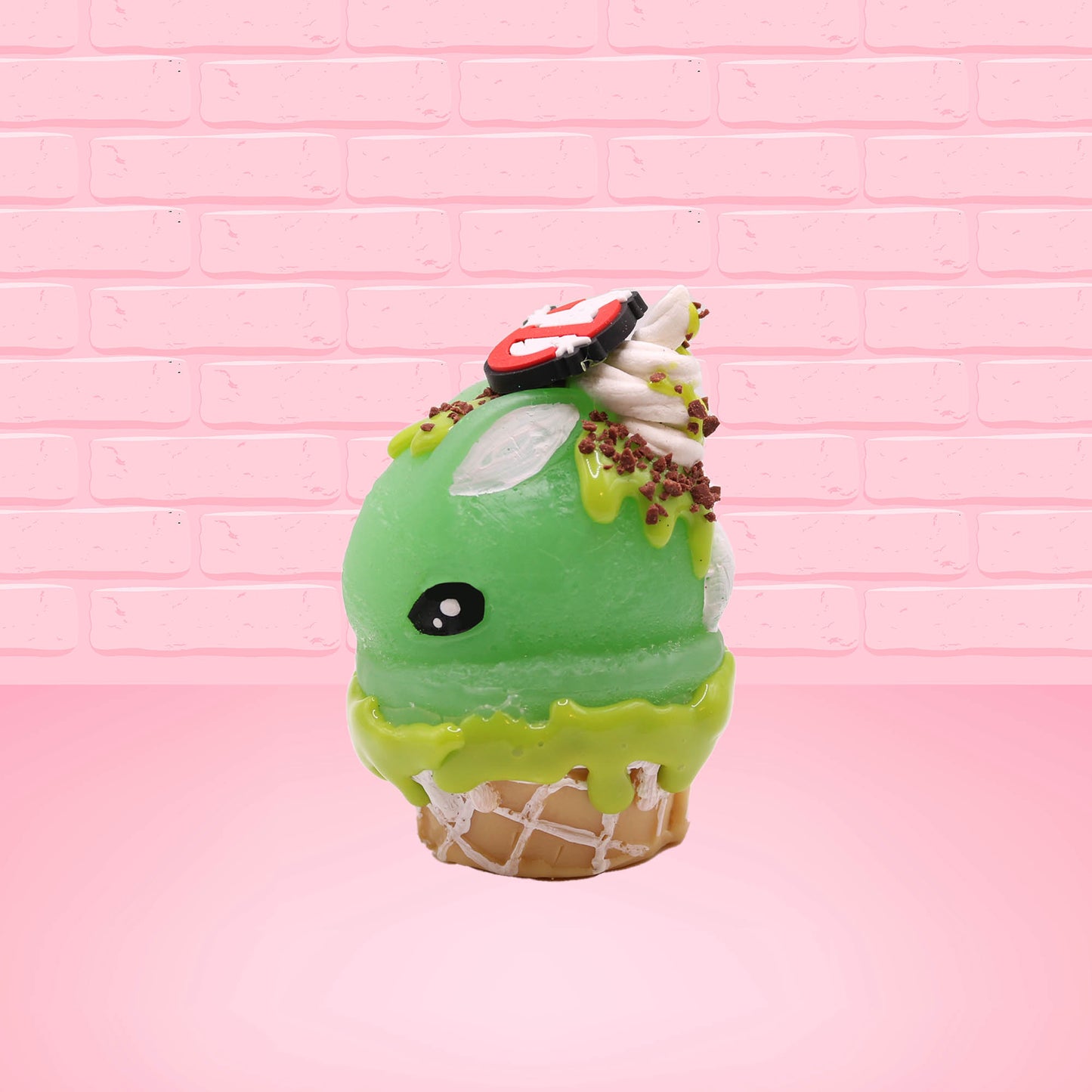 Cute kawaii bunny Slimer Scoop green ice cream cone with green drizzle and brown bits, a ghost buster logo near the whipped cream swirl on top. This view is from the other side.
