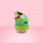 Cute kawaii bunny Slimer Scoop green ice cream cone with green drizzle and brown bits, a ghost buster logo near the whipped cream swirl on top. This view is from the other side.