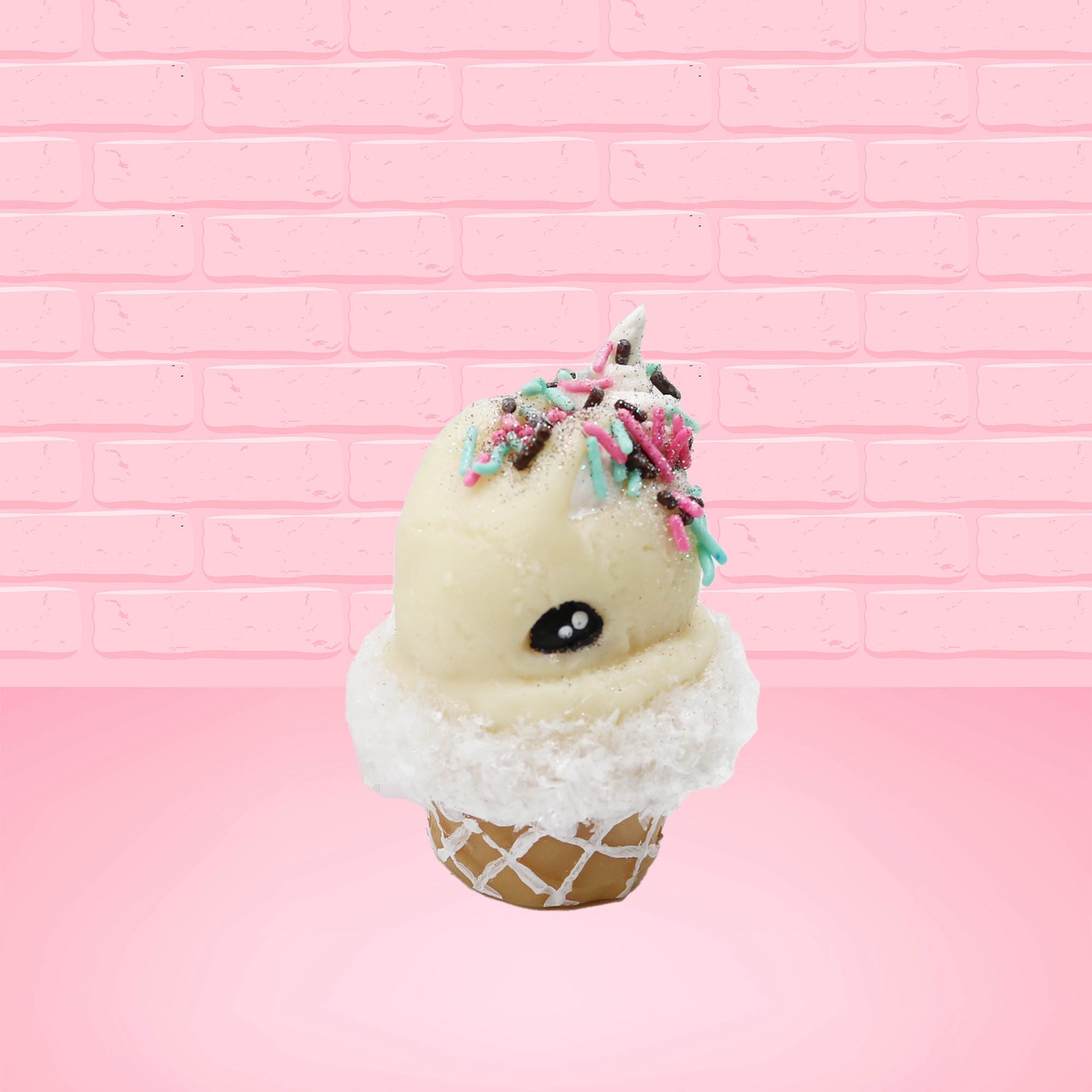 Cute kawaii bunny white ice cream cone with pink, teal, and black sprinkles on top of the bunny near the whipped cream swirl. The view is from the front at an angle. 