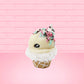 Cute kawaii bunny white ice cream cone with pink, teal, and black sprinkles on top of the bunny near the whipped cream swirl. The view is from the side. 
