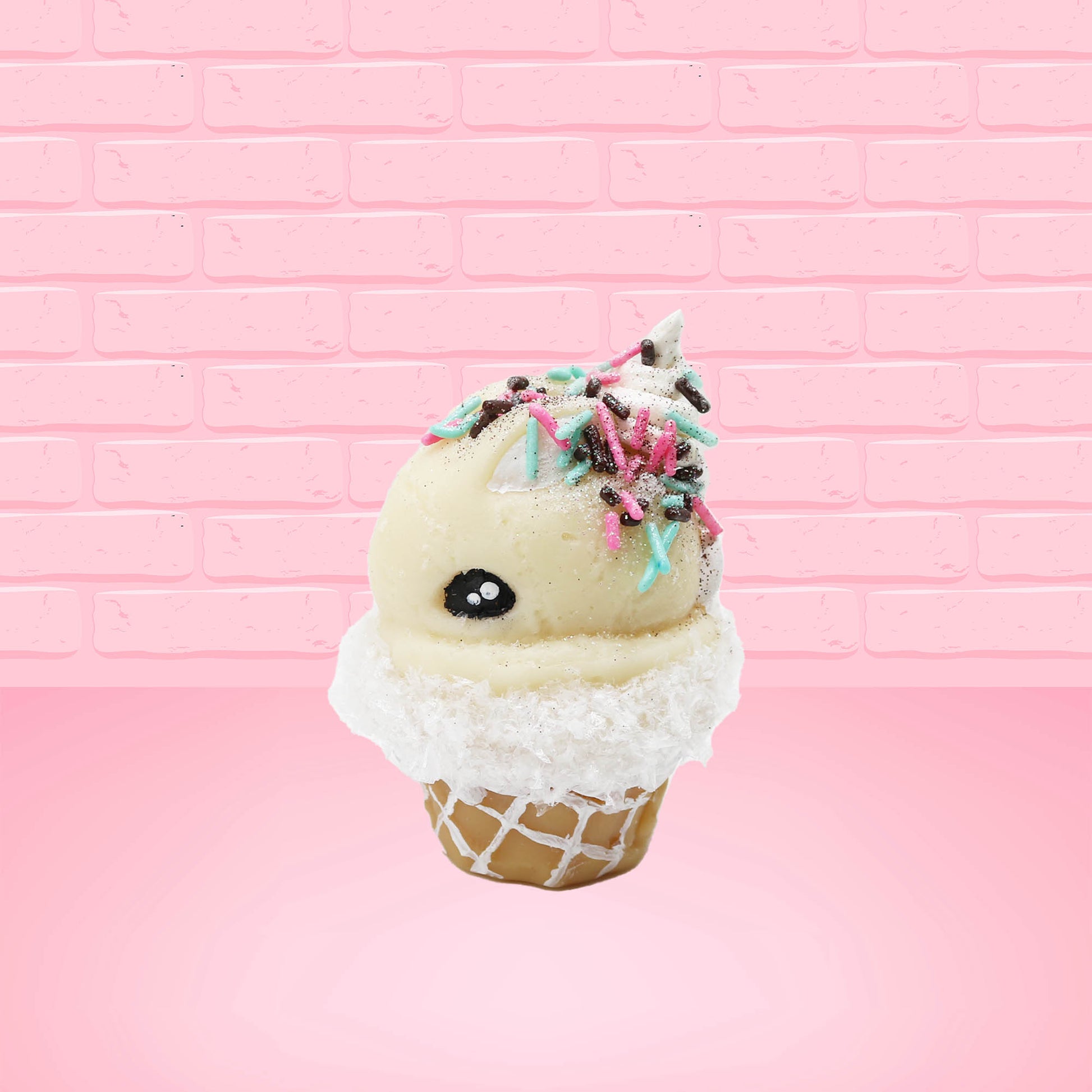 Cute kawaii bunny white ice cream cone with pink, teal, and black sprinkles on top of the bunny near the whipped cream swirl. The view is from the side. 