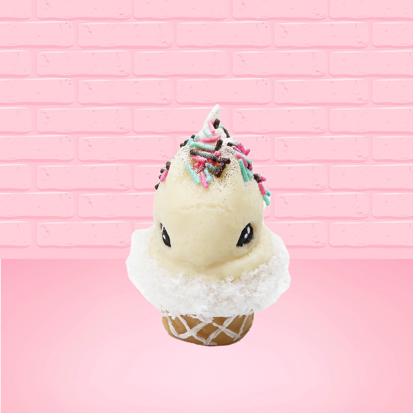 Cute kawaii bunny white ice cream cone with pink, teal, and black sprinkles on top of the bunny near the whipped cream swirl. The view is from the front. 