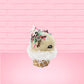 Cute kawaii bunny white ice cream cone with pink, teal, and black sprinkles on top of the bunny near the whipped cream swirl. The view is from the other side. 