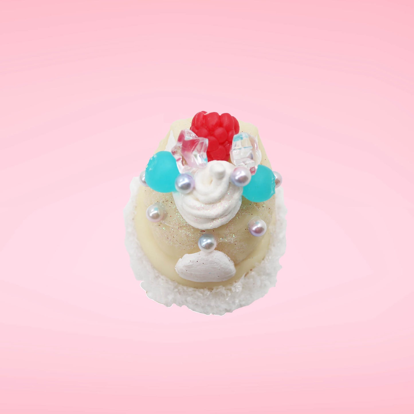 Cute kawaii bunny Vanilla Star Blast white ice cream cone with a blueberry, raspberry, and silver pearls near the swirl of whipped cream on the top of the bunny. This view is from the top.