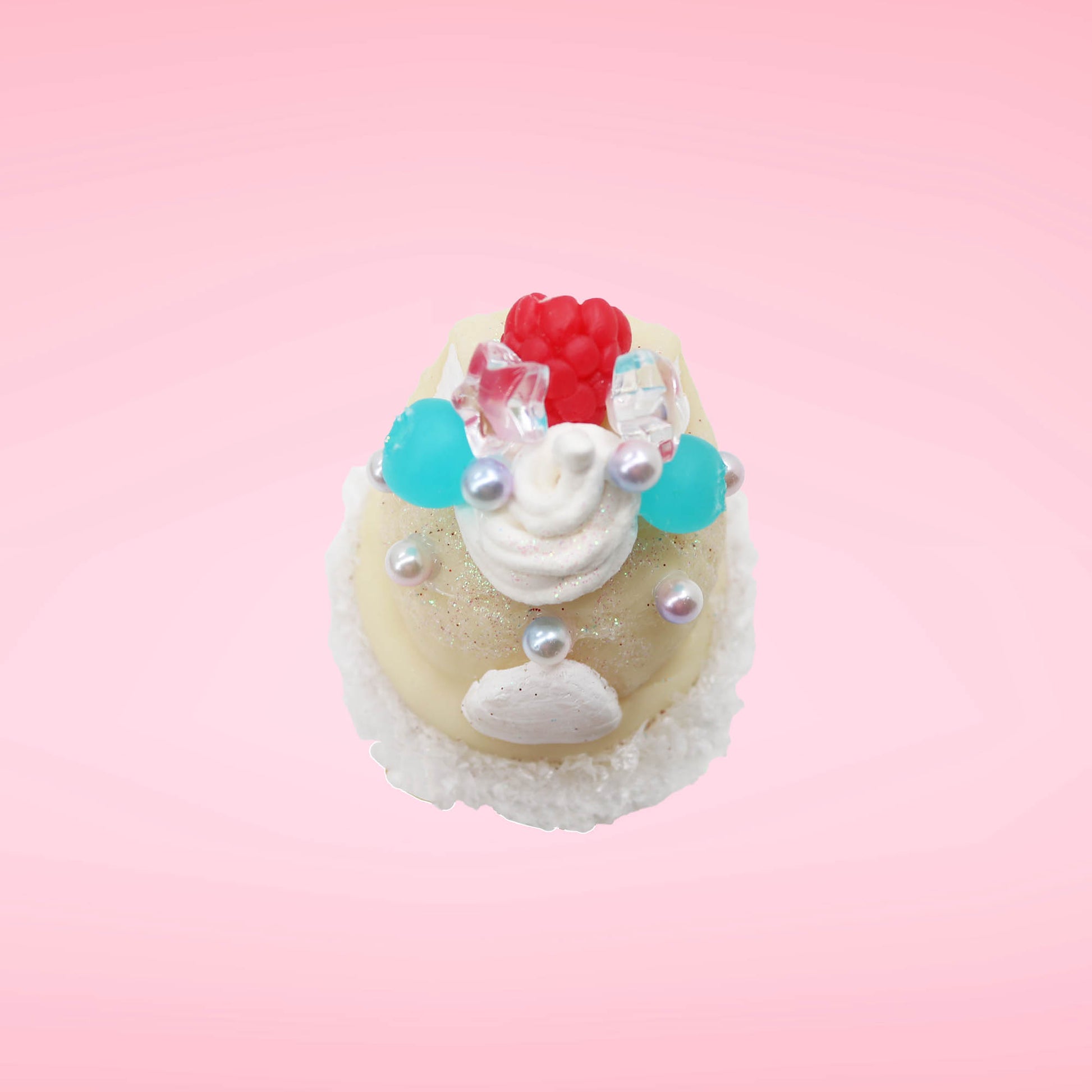 Cute kawaii bunny Vanilla Star Blast white ice cream cone with a blueberry, raspberry, and silver pearls near the swirl of whipped cream on the top of the bunny. This view is from the top.
