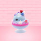 Cute kawaii Berry Swirl Cotton Candy blue ice cream sundae with pink glaze, pink blue and white sprinkles, strawberries and whipped cream swirls in the dish.  There are sprinkles, a blue berry, and strawberry on the top of the bunny near the swirl of the whipped cream. This view is from the side.