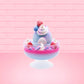Cute kawaii Berry Swirl Cotton Candy blue ice cream sundae with pink glaze, pink blue and white sprinkles, strawberries and whipped cream swirls in the dish.  There are sprinkles, a blue berry, and strawberry on the top of the bunny near the swirl of the whipped cream. This view is from the back.