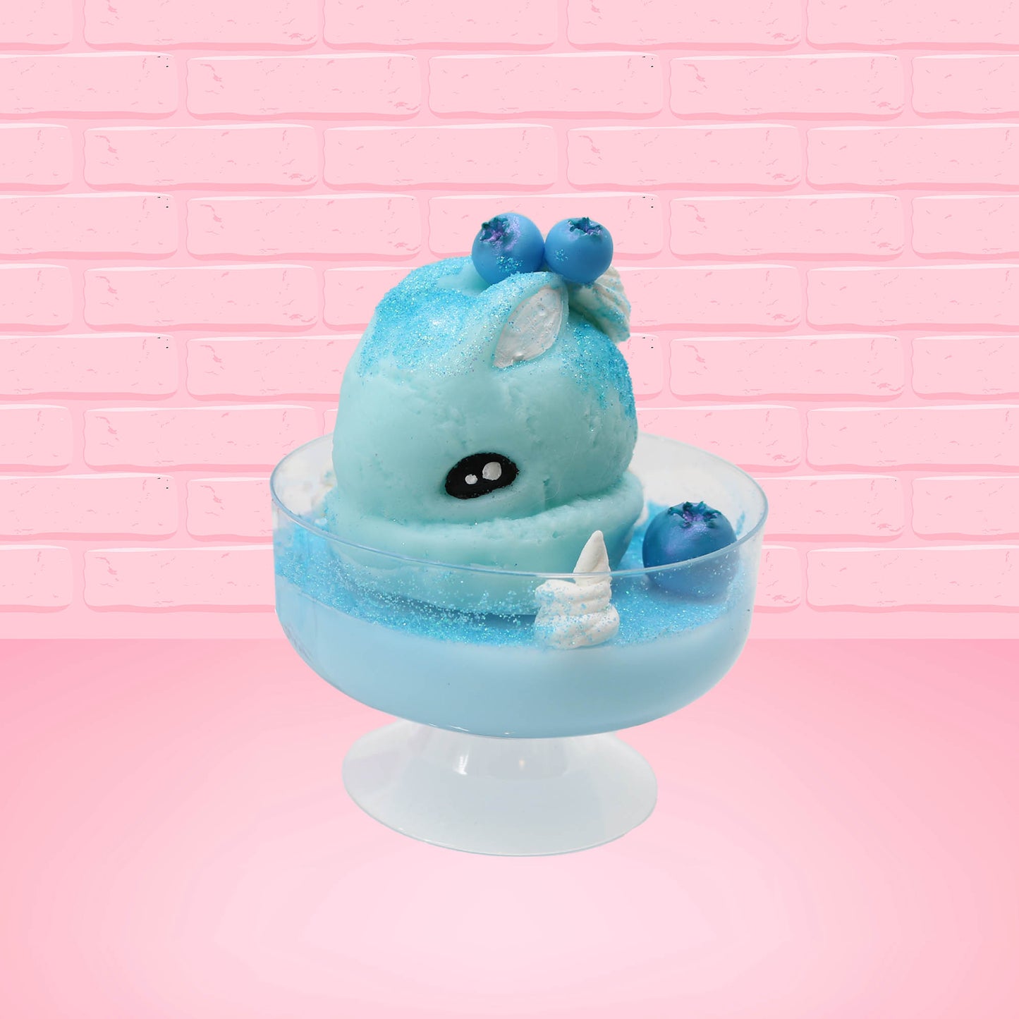 Cute kawaii Blue Berry Cotton Candy ice cream sundae with blue berries and swirls of whipped cream in the dish, while covered with blue glitter. The bunny has two blue berries on the top near the swirl of whipped cream on the back. This view is from the front and a little to side.
