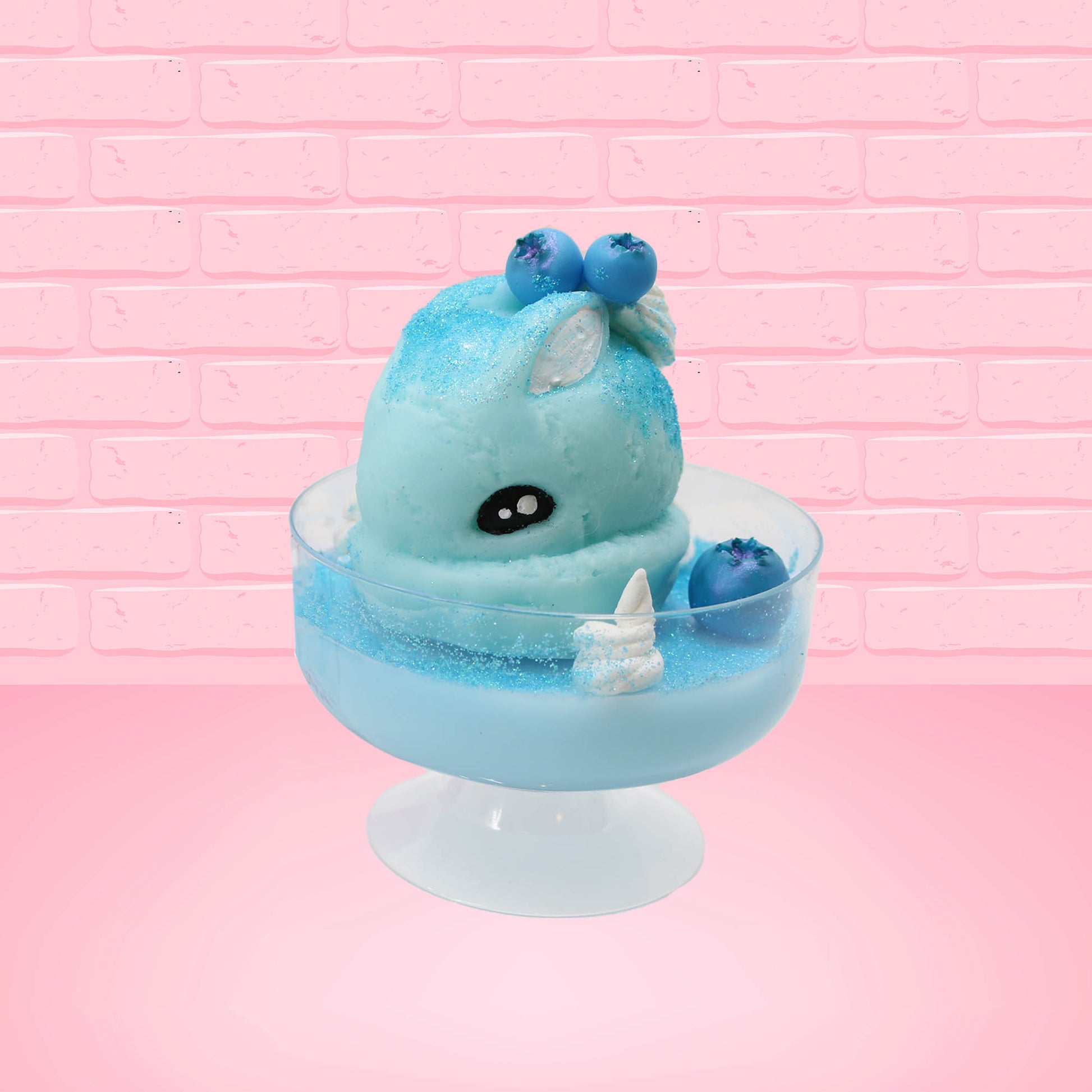 Cute kawaii Blue Berry Cotton Candy ice cream sundae with blue berries and swirls of whipped cream in the dish, while covered with blue glitter. The bunny has two blue berries on the top near the swirl of whipped cream on the back. This view is from the front and a little to side.