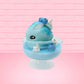Cute kawaii Blue Berry Cotton Candy ice cream sundae with blue berries and swirls of whipped cream in the dish, while covered with blue glitter.  The bunny has two blue berries on the top near the swirl of whipped cream on the back. This view is from the side.