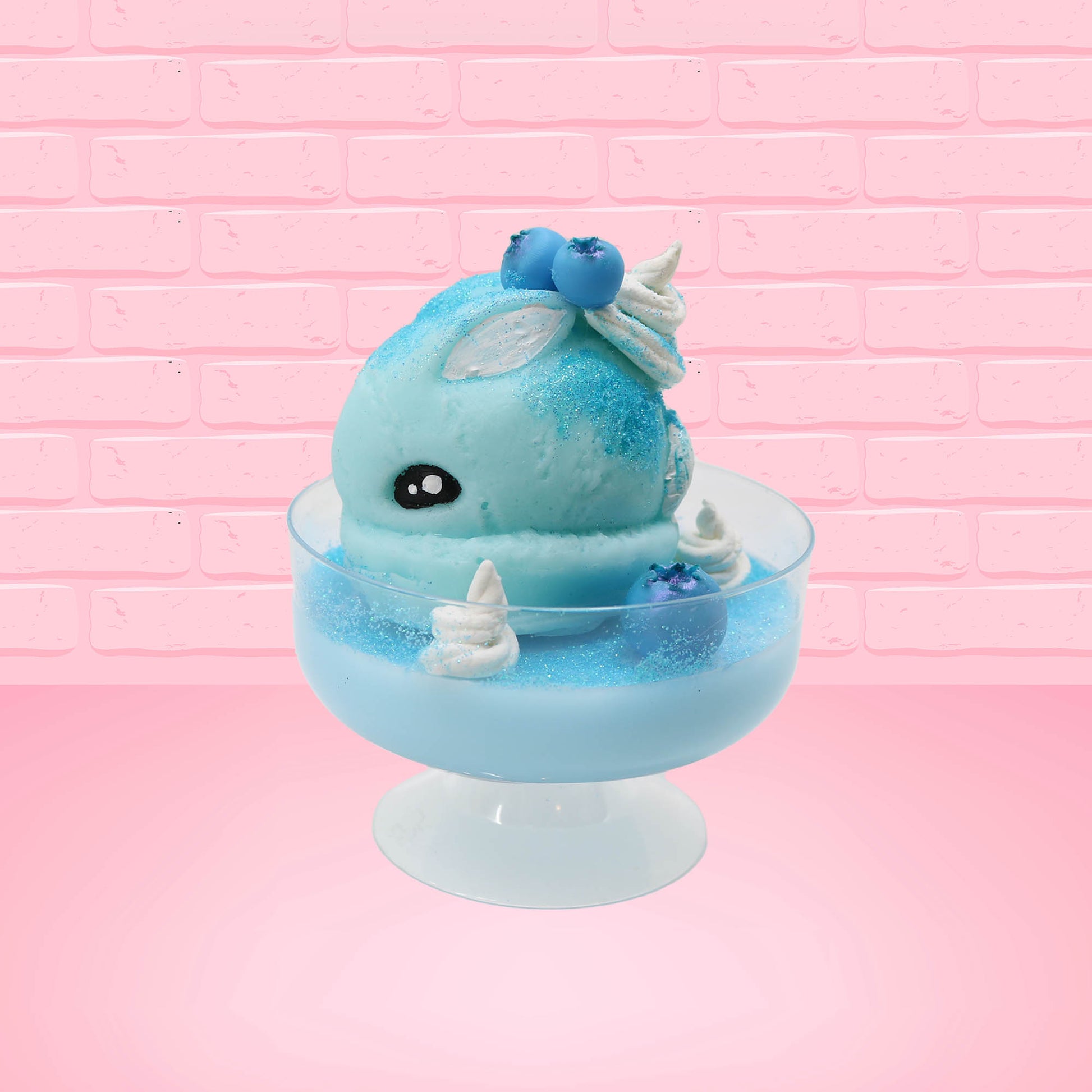 Cute kawaii Blue Berry Cotton Candy ice cream sundae with blue berries and swirls of whipped cream in the dish, while covered with blue glitter.  The bunny has two blue berries on the top near the swirl of whipped cream on the back. This view is from the side.