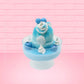Cute kawaii Blue Berry Cotton Candy ice cream sundae with blue berries and swirls of whipped cream in the dish, while covered with blue glitter.  The bunny has two blue berries on the top near the swirl of whipped cream on the back. This view is from the back.